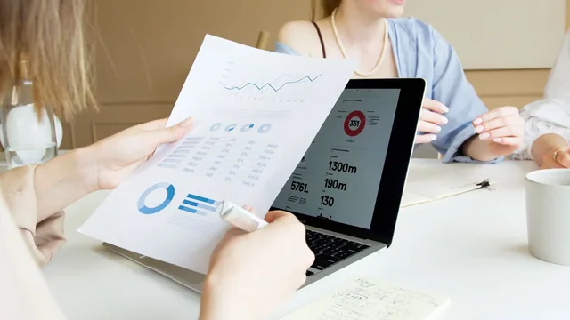Two people reviewing printed charts and financial records