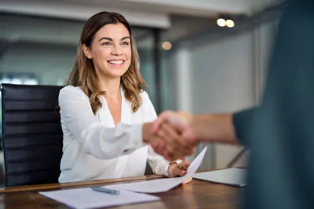 Participants greeting each other across a desk before a meeting