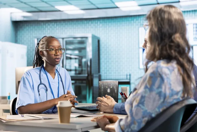 A healthcare professional speaking with a patient across a desk