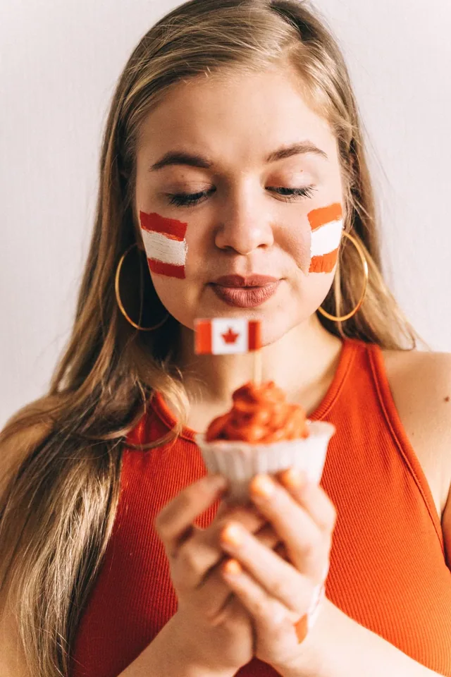 A woman with Canadian flag face paint at a celebration