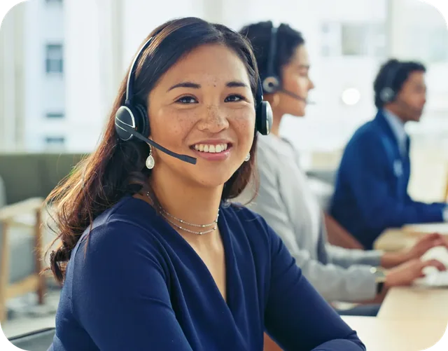 A headset professional at a workstation with colleagues nearby