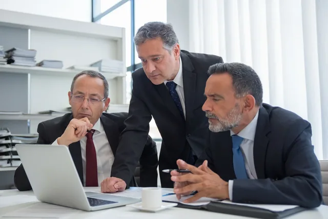 Professionals reviewing material together at a laptop