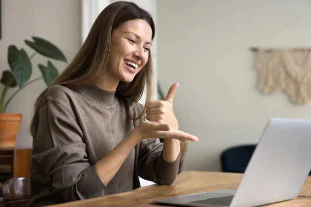 A woman signing while communicating through a laptop