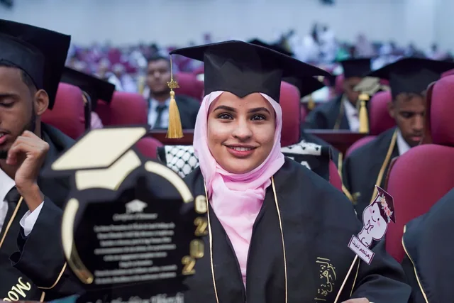 Crest translation services: a smiling graduate holding her diploma at a graduation ceremony