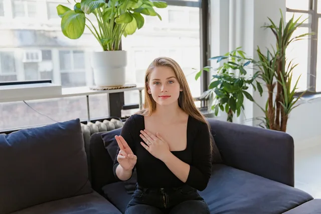Crest interpreting services: a woman communicating in sign language in a seating area