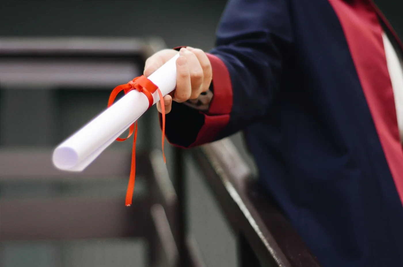 A graduate holding a rolled diploma