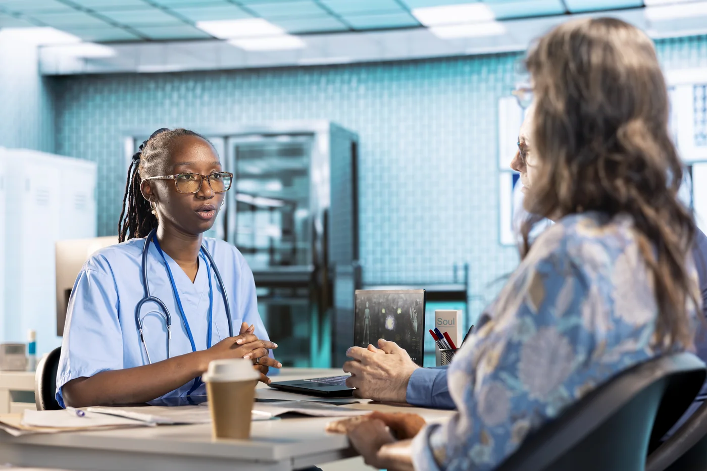 A healthcare professional speaking with a patient across a desk