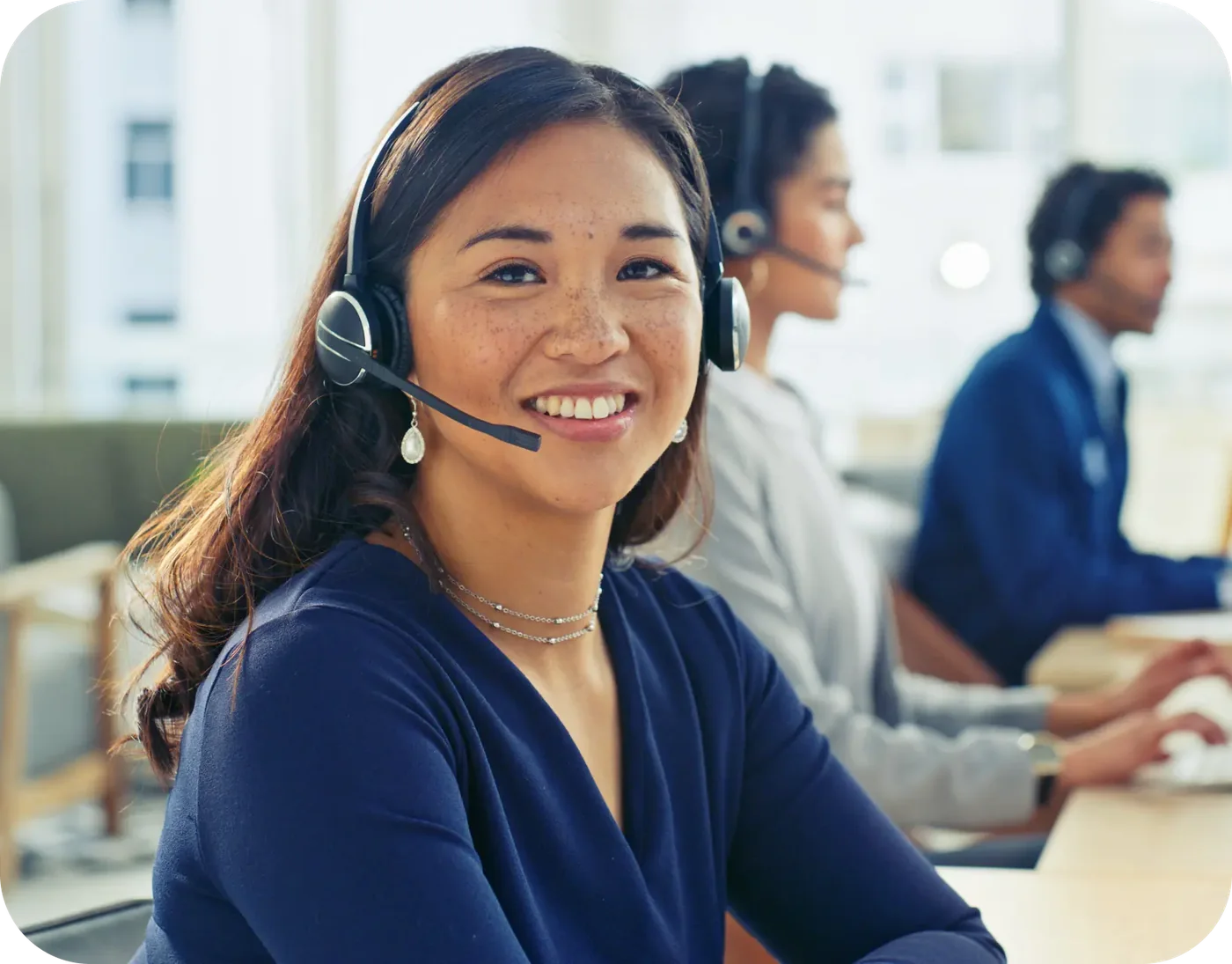 A headset professional at a workstation with colleagues nearby