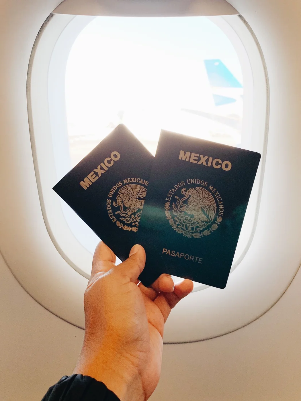 Closed passports held beside an aircraft window